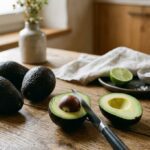 Frische Avocados und eine aufgeschnittene Avocado auf einem Holztisch