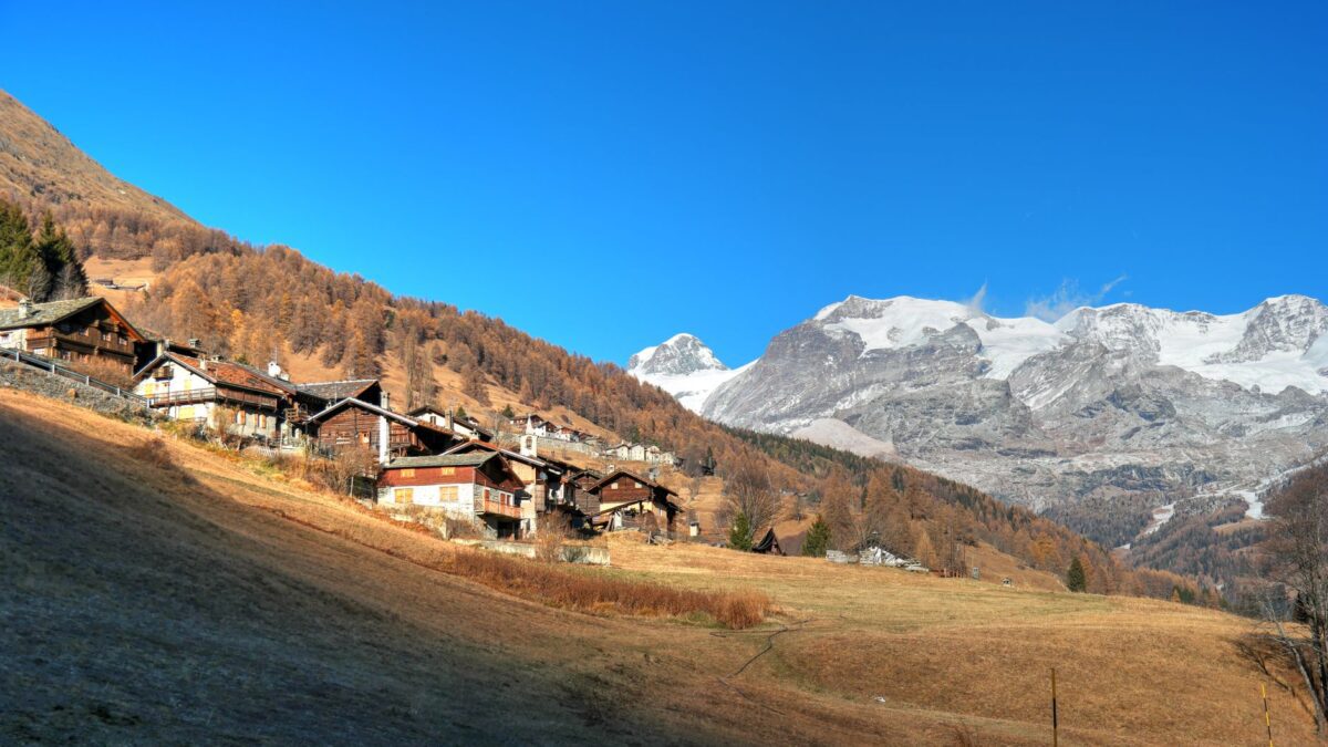 Wohnhäuser in einer Schweizer Gemeinde vor herbstlicher Berglandschaft