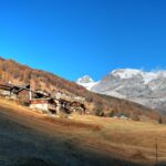 Wohnhäuser in einer Schweizer Gemeinde vor herbstlicher Berglandschaft