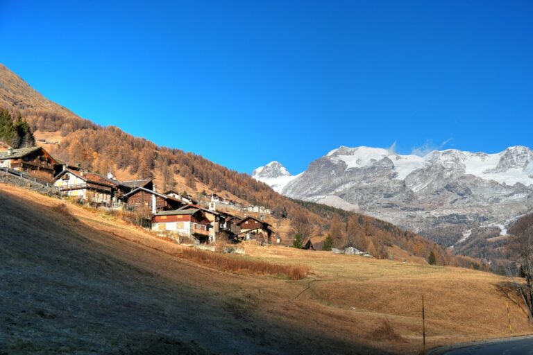 Wohnhäuser in einer Schweizer Gemeinde vor herbstlicher Berglandschaft