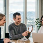 Drei Büroangestellte besprechen einen Firmen-Mobilfunk-Vertrag mit Blick auf die Schweizer Alpen