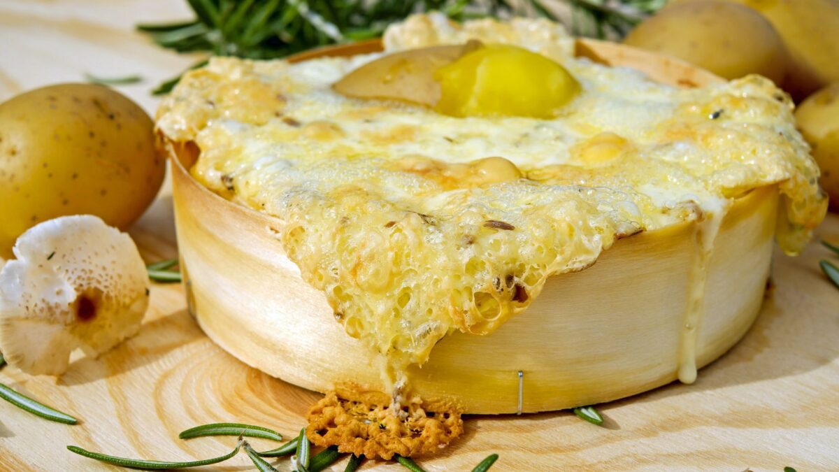 Geschmolzener Raclettekäse wird über Kartoffeln geschabt