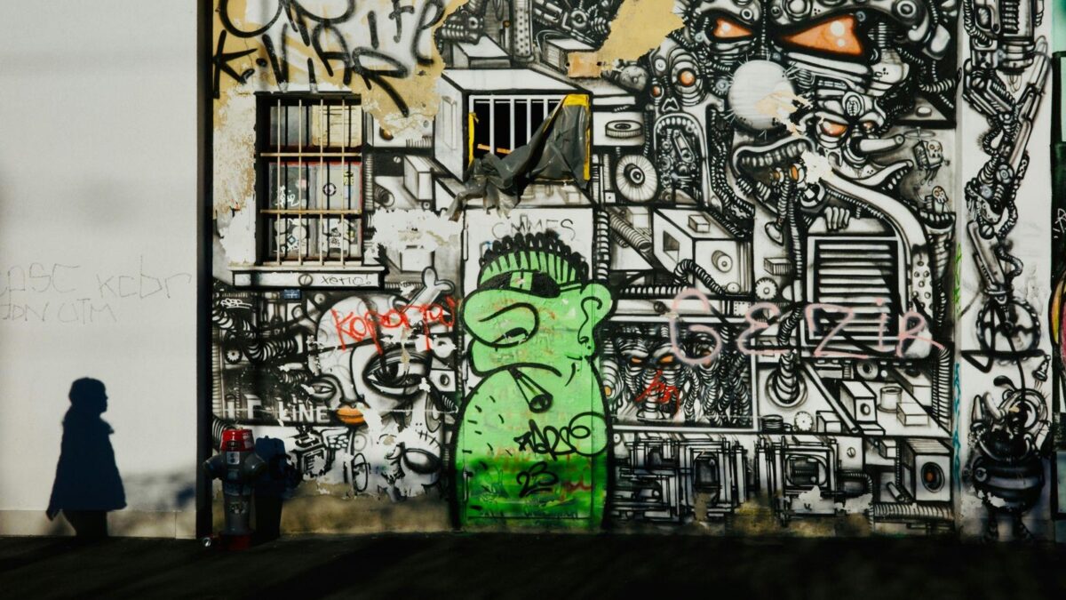 Schatten einer Person vor einer grossflächig mit Graffiti bemalten Hauswand