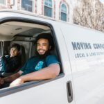 Zwei Personen tragen ein Sofa zu einem Lieferwagen