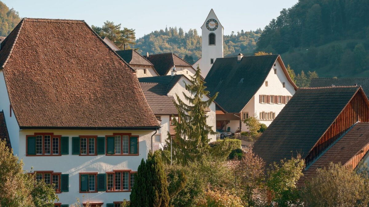 Wohnhäuser in einem Schweizer Dorf vor einer Bergkulisse